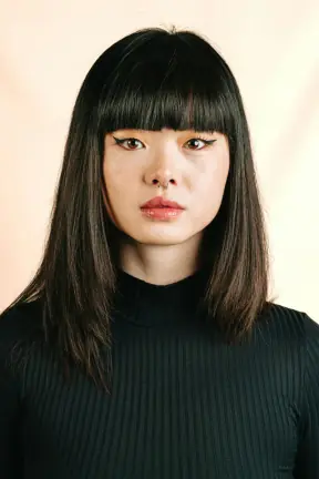 Blunt bangs grown out into center-parted waves